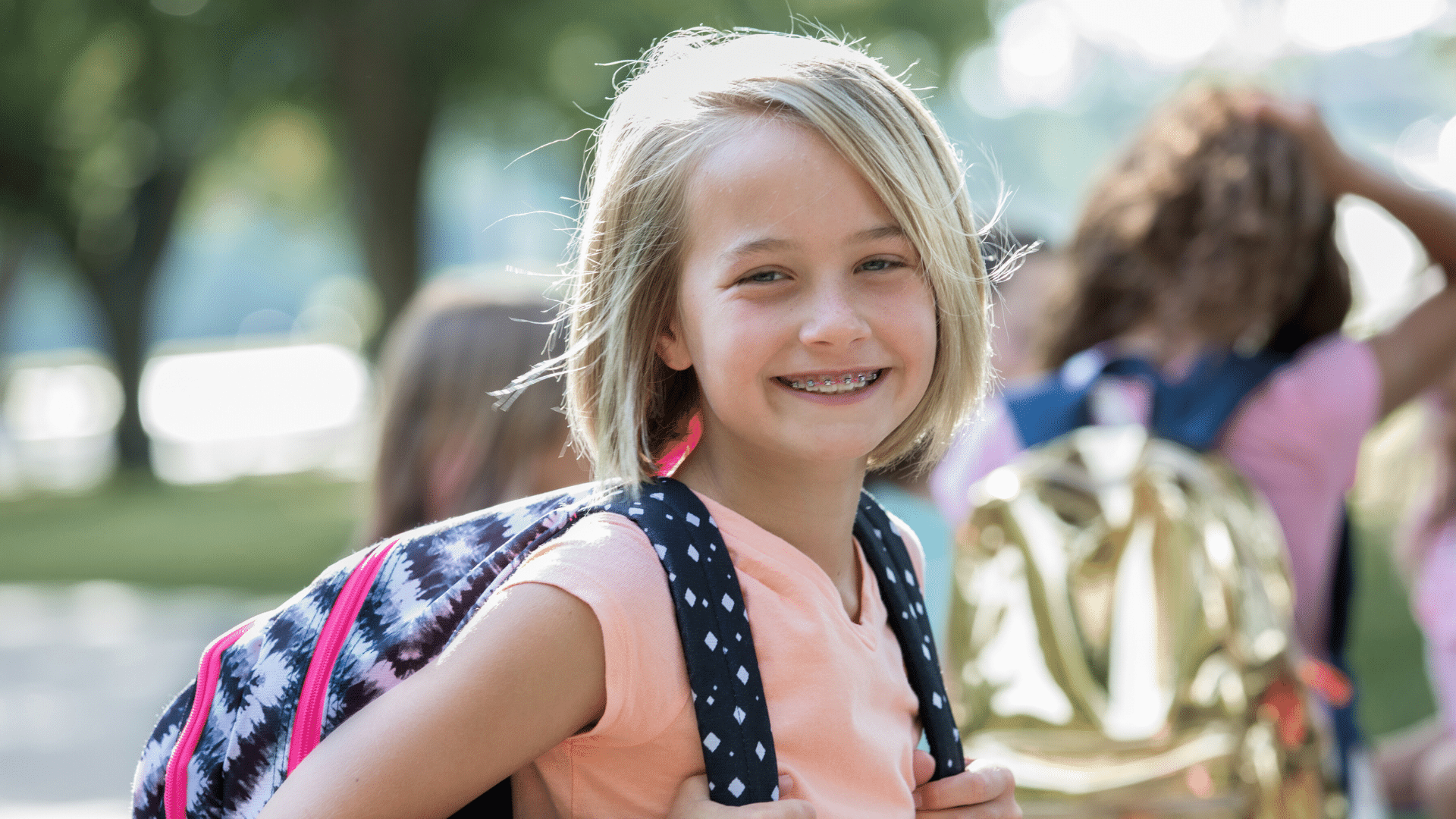 Smiling young girl with backpack for early orthodontic treatment at Bernhardt & Smith Orthodontics, Bishop Drive Office and 50th Street Office in West Des Moines, IA
