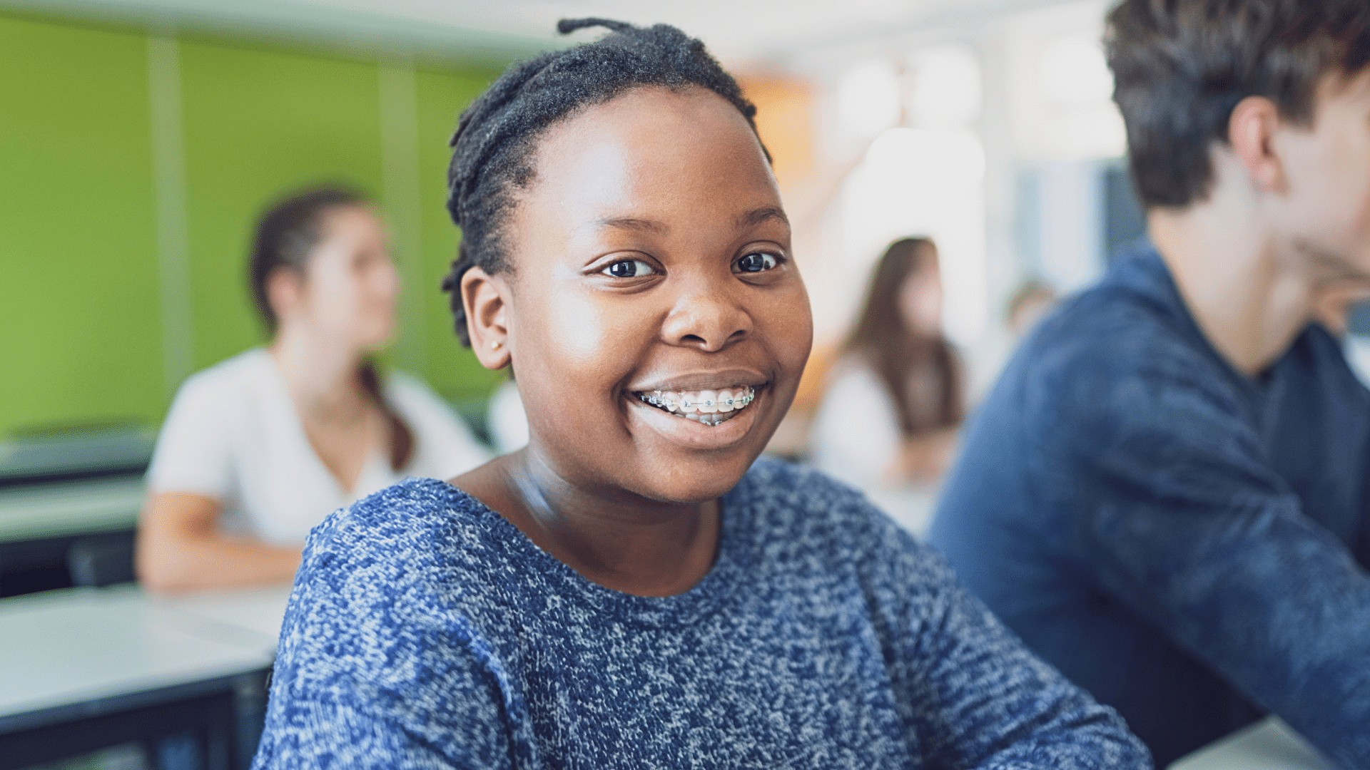 Smiling teen patient wearing braces in a classroom setting at Bernhardt & Smith Orthodontics, Bishop Drive Office and 50th Street Office in West Des Moines, IA