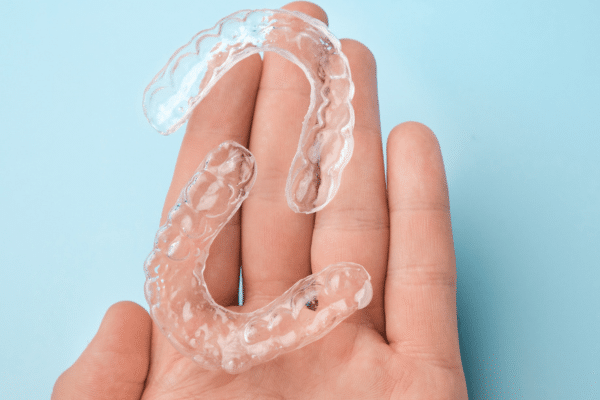 Clear Invisalign aligners held in hand at Bernhardt & Smith Orthodontics, Bishop Drive Office and 50th Street Office in West Des Moines, IA